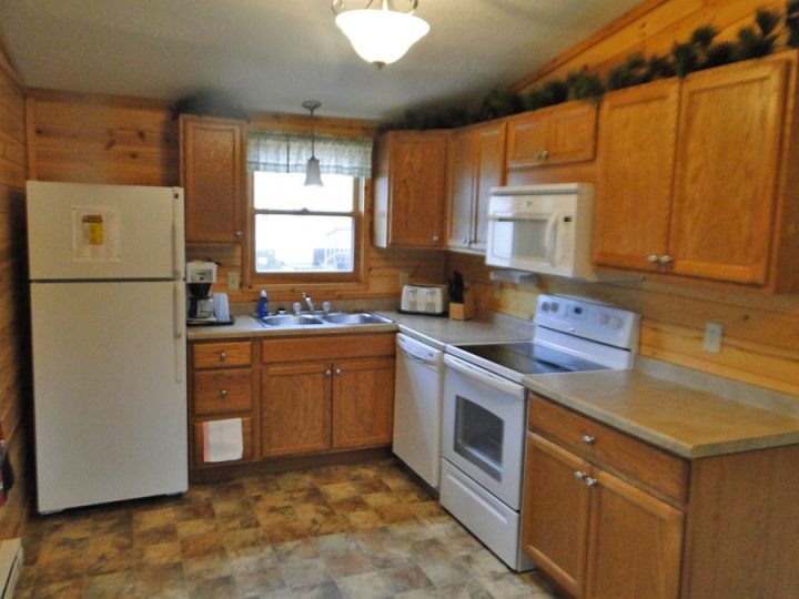 Cozy cabin kitchen with wood cabinets and white appliances