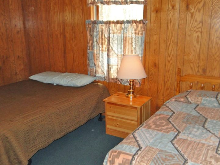 Cozy rustic cabin bedroom with two beds and wood paneling