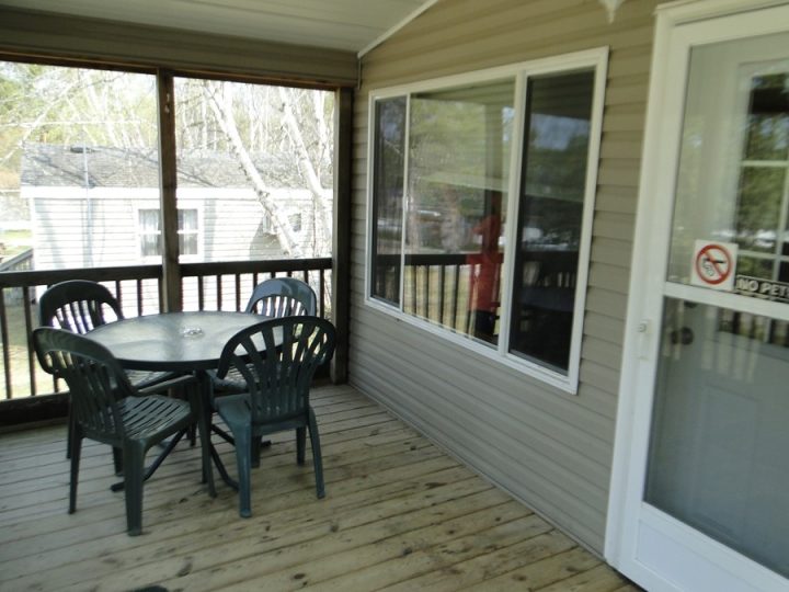 Covered deck with green plastic patio table and chairs
