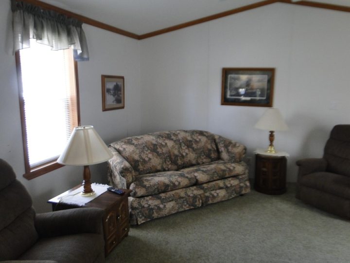 Cozy living room with floral sofa, recliners, and lamp