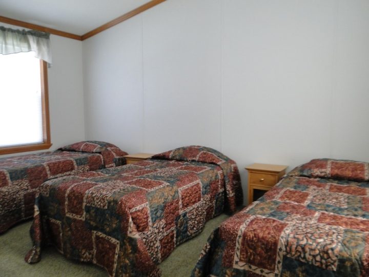 Simple bedroom with three beds and matching patterned bedspreads